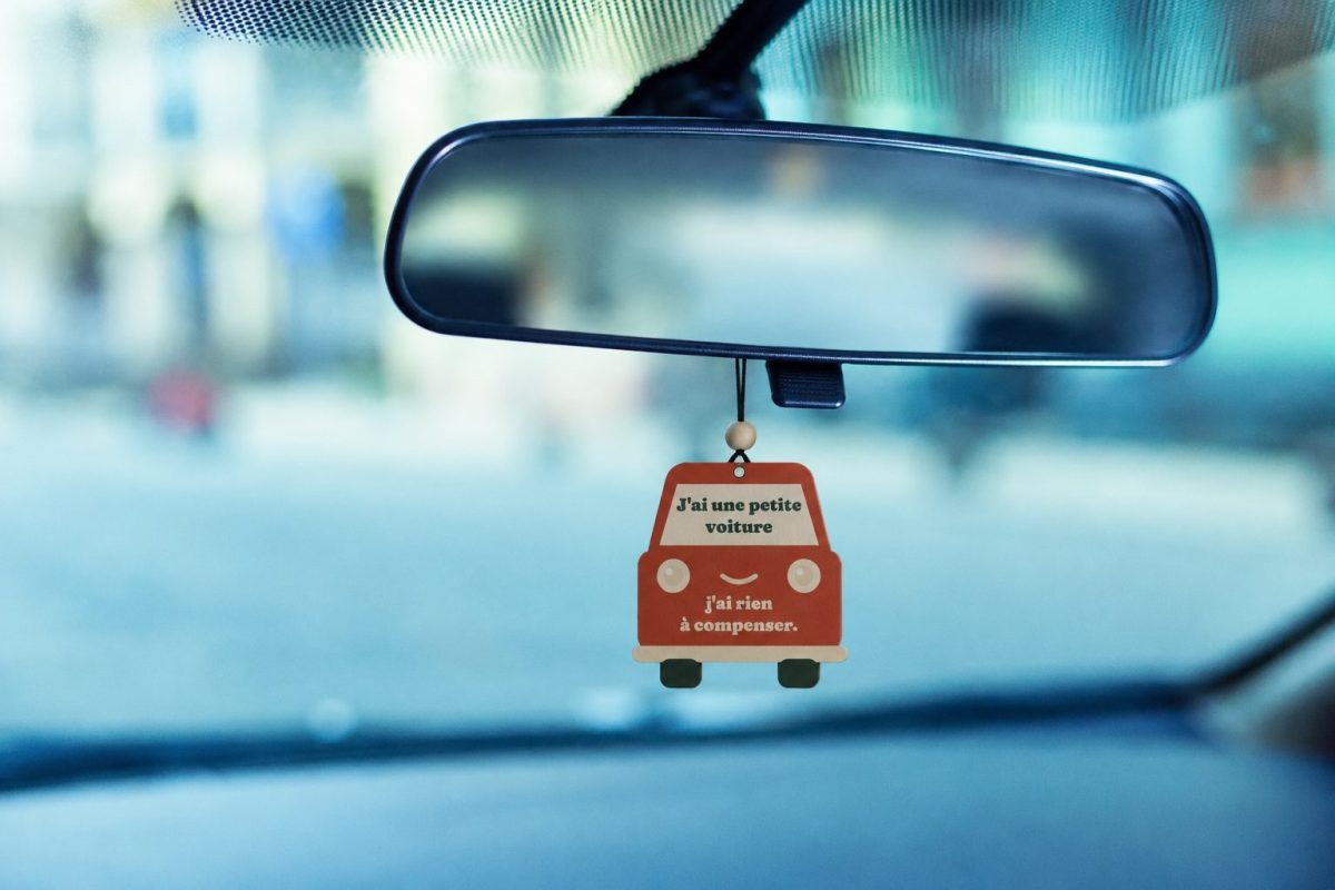 Sent-bon J'ai une petite voiture en forme de petite voiture rouge souriante, suspendu au rétroviseur d'une voiture